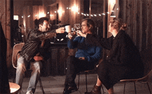 a group of people are sitting in chairs toasting with cups of coffee