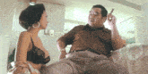 a man smoking a cigar next to a woman in a black bra