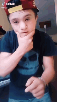 a young boy wearing a hat and a t-shirt is making a funny face .