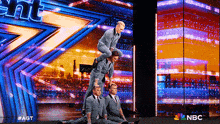 a group of men are performing on a stage with a nbc logo behind them
