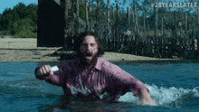 a man in a pink shirt is swimming in a body of water with # 28yearslater written above him