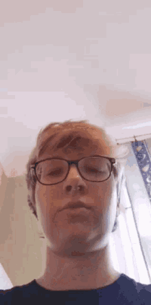 a man wearing glasses and a nose ring is looking at the camera .