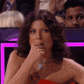 a woman in a red dress with a necklace on her neck looks at the camera