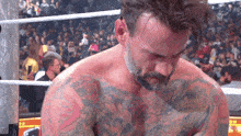 a man in a wrestling ring has a tattoo on his chest that says ' a ' on it