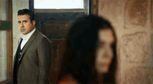 a man in a suit is standing next to a woman in a doorway .