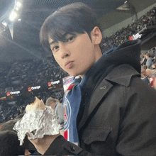 a young man is holding a piece of aluminum foil in front of a crowd at a stadium .