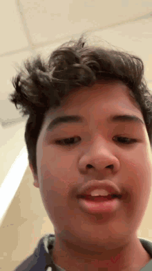 a young man with curly hair is making a funny face while looking at the camera .