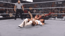 two women are wrestling in a wrestling ring with a referee watching .