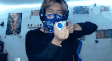 a man wearing a mask and headphones is holding a white object