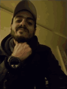 a man with a beard wearing a hat and a black jacket