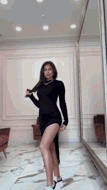 a woman in a black dress standing in front of a mirror