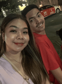 a man and a woman are posing for a picture in front of a taxi that has the number 6 on the side