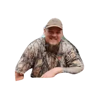 a man wearing a camo shirt and hat with a deer on it