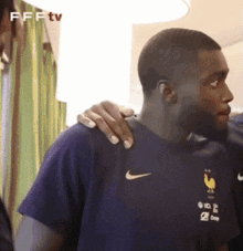 a man wearing a blue nike shirt is being comforted by another man