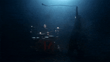 a man is holding a microphone in front of a drum set that has the letter h on it