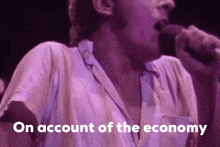a man singing into a microphone with the words " on account of the economy " below him