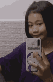 a girl is taking a picture of herself in the mirror with a doraemon phone case .