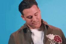 a man wearing a jacket with a rose embroidered on the front