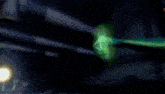 a green light is glowing in the dark behind a fence .