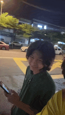 a boy with long hair is smiling while holding a phone