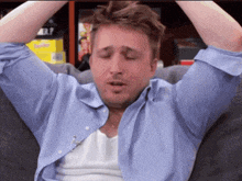 a man sitting on a couch with his eyes closed and his hands on his head