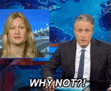 a man in a suit and tie says why not while a woman looks on