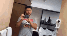 a man in a mickey mouse shirt takes a picture of himself in a mirror
