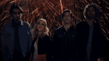 a group of people are standing in front of fireworks .