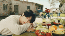 a man laying on a table with tomatoes and fruit
