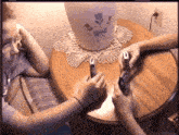two people are sitting at a table looking at their cell phones and a vase with flowers on it