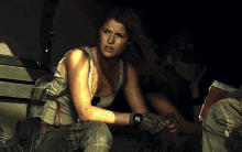 a woman wearing a glove that says ' tactical ' on it sits next to another woman