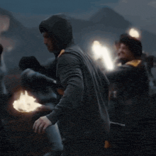 a man in a hooded sweatshirt is holding a torch in his hand .