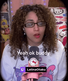 a woman with curly hair wearing glasses and a hello kitty shirt says " yeah ok buddy "