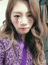 a woman in a purple jacket is taking a selfie with her eyes closed .