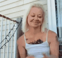 a woman with a tattoo on her chest is smiling while sitting on a porch .