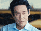 a close up of a man 's face with a blue shirt