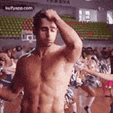 a shirtless man is standing in front of a crowd of people in a stadium .