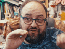 a man with glasses and a beard is wearing headphones and making a funny face