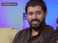 a man with a beard is smiling for the camera .