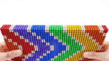 a person is holding a stack of colorful beads that are made in animotica