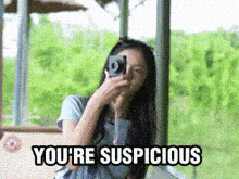 a woman taking a picture with a camera and the words you 're suspicious below her