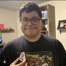 a man wearing glasses and a sonic the hedgehog t-shirt is holding a sticker .