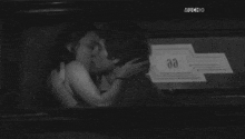 a man and woman kissing in front of a sign that says muchhd