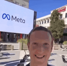 a man is smiling in front of a large screen that says meta