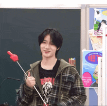 a young man in a plaid jacket is holding a red balloon in his hand .