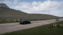 two cars are driving down a road with a mountain in the background
