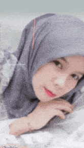 a close up of a woman wearing a gray hijab with a red arrow pointing to her face