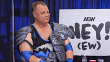 a wrestler is sitting in front of a sign that says " hey "