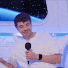 a man is holding a microphone and smiling while sitting in a chair .