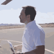 a man in a white shirt holds a piece of paper in his hand